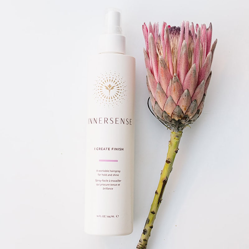 Beauty shot of Innersense Organic Beauty I Create Finish 10 oz with pink flower next to product
