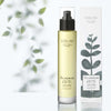 Lifestyle shot of Olverum The Dry Body Oil (100 ml) and box with leaves in the background