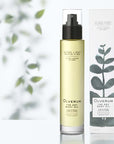 Lifestyle shot of Olverum The Dry Body Oil (100 ml) and box with leaves in the background