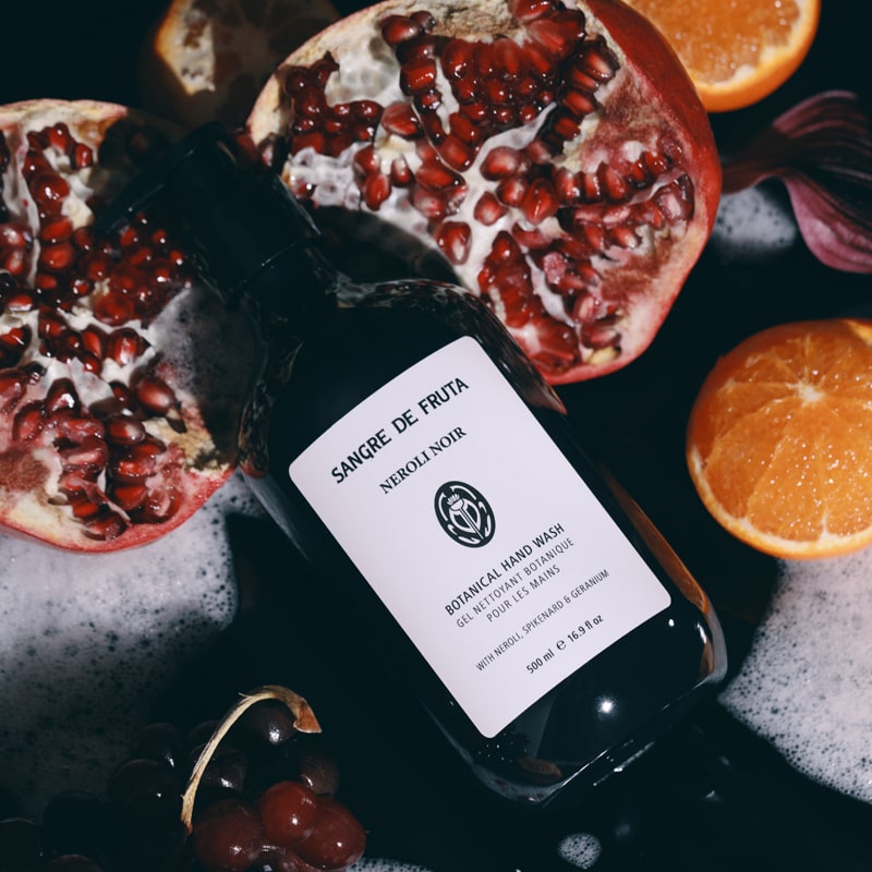 Lifestyle shot of Sangre de Fruta Botanical Hand Wash Neroli Noir (500 ml) top view with oranges and pomegranate in the background