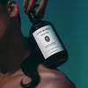 Lifestyle shot of Sangre de Fruta Botanical Shampoo Neroli Noir (500 ml) resting on the shoulder of model