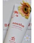 Rosebud Woman Soothe Calming Cream beauty shot with a flower over the cream tube