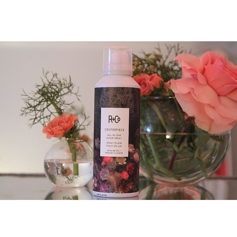 R+Co Centerpiece All-In-One Elixir Spray next to flowers