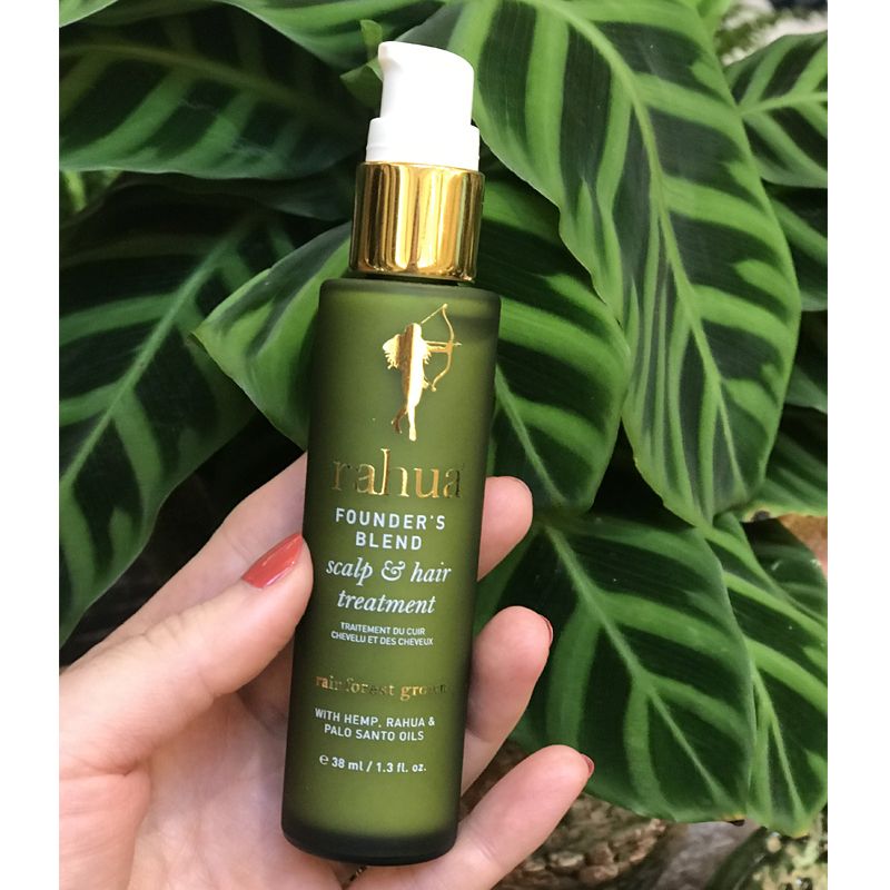 Beauty shot of Rahua by Amazon Beauty Founder's Blend Scalp & Hair Treatment (38 ml) bottle in hand of model with green leaves in the background