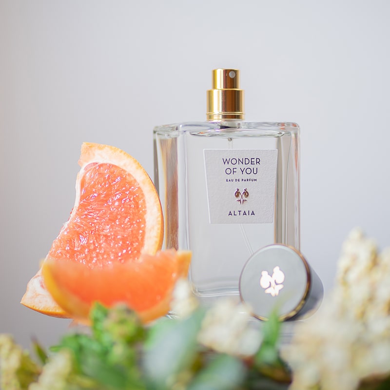 Lifestyle shot of ALTAIA Wonder of You Eau de Parfum (100 ml) with citrus slices and ingredients in the foreground