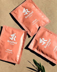 Rosebud Woman Refresh Intimate and Body Cleaning Wipes - beauty shot of 3 packets on sand