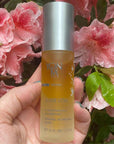 Yon-Ka Paris Elixir Vital (30 ml) in hand of model with pink flowers in the background