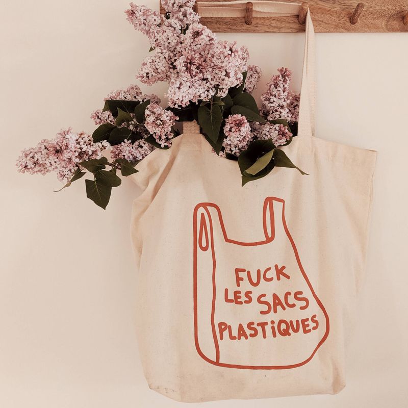 Mimi &amp; August F&amp;$! Plastique French Printed Cotton Tote Bag hanging on a hook with flowers in it