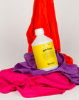 Kerzon Fragranced Laundry Soap - Gym Tonique (16.67 oz) sitting on a pile of vibrant clothes