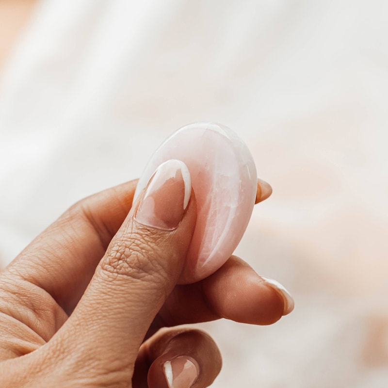 Tiny Rituals Rose Quartz Worry Stone - shown in use by model hand
