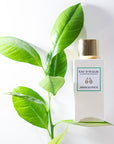 Lifestyle shot of Eau d'Italie Jardin du Poete Eau de Parfum Spray (100 ml) with green leaves in the background