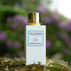Lifestyle shot of Eau d'Italie Jardin du Poete Eau de Parfum Spray (100 ml) with purple flowers in the background