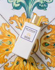 Lifestyle shot top view of Eau d'Italie Un Bateau Pour Capri Eau de Parfum Spray (100 ml) on tile with yellow flowers