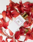Lifestyle shot top view of Eau d'Italie Graine de Joie Eau de Parfum Spray (100 ml) with red flower petals in the background