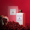 Lifestyle shot of Eau d'Italie Graine de Joie Eau de Parfum Spray (100 ml) with box and pomegranate and seeds in the foreground