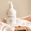 Lifestyle shot of Minois Paris Lait Corps (Body Lotion) (500 ml) with cloth in the background