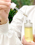 Athar’a Pure Neem Healing Oil in model's hands with dropper
