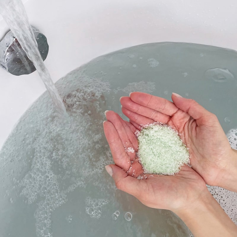 Odacite Energy Awakening Evergreen Bath Soak (8 oz) model placing bath salt in into bath