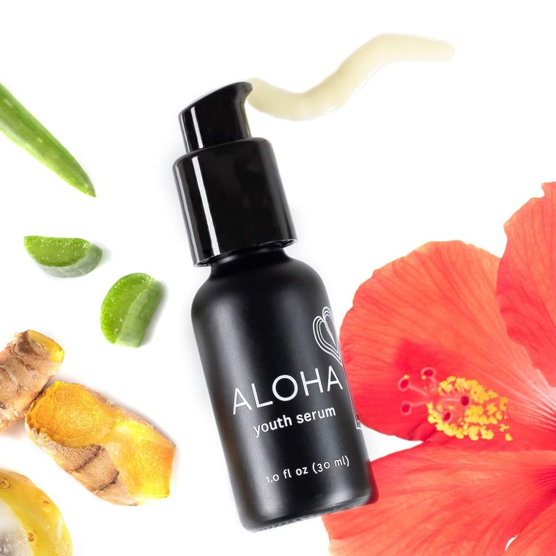 Honua Hawaiian Skincare Aloha Youth Serum pictured with Hibiscus flower and other ingredients for beauty shot
