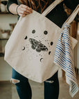Mineral and Matter Moth and Moons Tote Bag - shown in model's hands with a scarf tied for flair (not included)