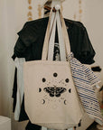 Mineral and Matter Moth and Moons Tote Bag - shown hanging on a rack with clothing and with a scarf tied for flair (not included)
