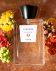 ALTAIA Atacama Eau de Parfum beauty shot on pile of Himalayan Pink Salt and yellow, red and green flowers in the background