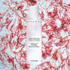 Chantecaille Purifying and Exfoliating Phytoactive Solution beauty shot with pink flowers in background