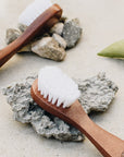 Annmarie Skin Care Lotus Wood Exfoliating Brush shown with rocks and another brush - each sold separately