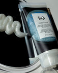 R+Co Submarine Water Activated Enzyme Exfoliating Shampoo showing a squiggle of the shampoo on a mirror beside tube