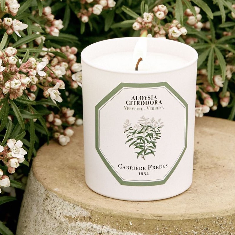 Lifestyle shot of Carriere Freres Verbena Candle with flowers in background