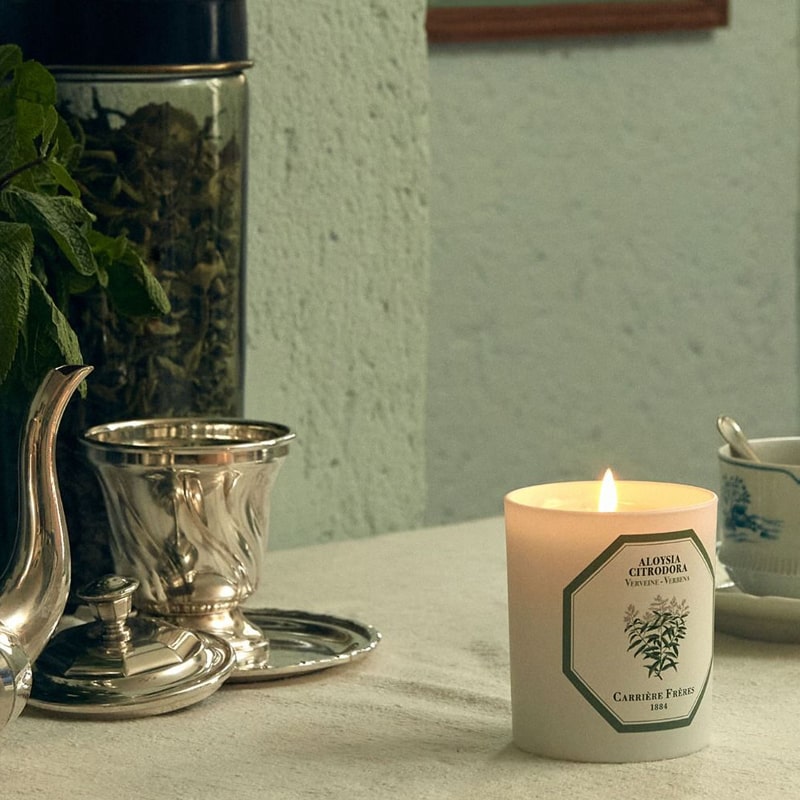 Lifestyle shot of Carriere Freres Verbena Candle showing candle lit with teapot and cup in background