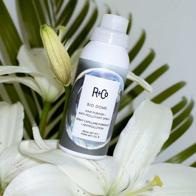 R+Co Bio Dome Hair Purifier + Anti-Pollutant Spray beauty shot with plants and flowers