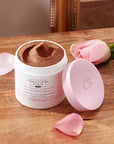 Christophe Robin Cleansing Volumizing Paste with Pure Rassoul Clay and Rose Extracts beauty shot of an open jar on a table with rose and petals
