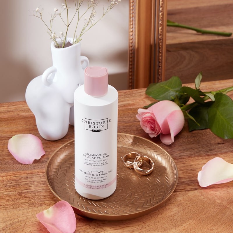 Christophe Robin Delicate Volume Shampoo with Rose Extracts pictured on tray with rose and earrings nearby