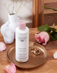 Christophe Robin Delicate Volume Shampoo with Rose Extracts pictured on tray with rose and earrings nearby
