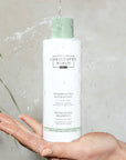 Christophe Robin Hydrating Shampoo with Aloe Vera shown in model's hand with water pouring on it