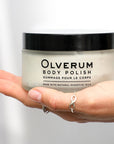Olverum Body Polish closed jar shown in model's open palm