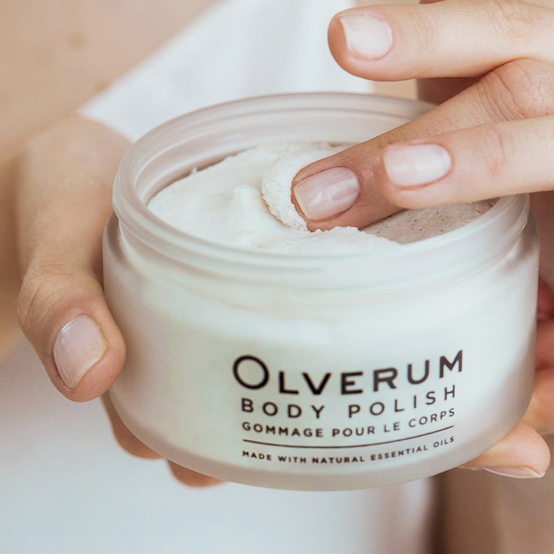 Olverum Body Polish shown in model&#39;s hand scooping product out with fingers