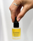Olverum Pure Radiance Facial Oil with model's hand grasping top of dropper on closed bottle
