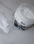 R+Co HYPERLINK Fiber Stretch Pomade showing open jar and product smear on marble slab
