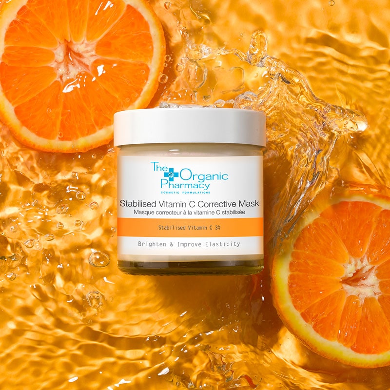 The Organic Pharmacy Stabilized Vitamin C Corrective Mask beauty shot in water beside orange slices