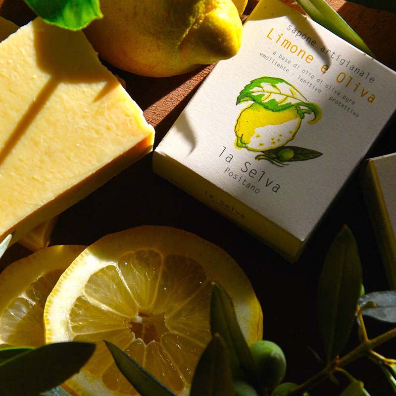La Selva Positano Cosmetici Naturali Lemon and Olive Solid Soap displayed outside of the box surrounded by fresh lemons