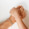 Blu Kat Kids Rose Quartz Bracelet shown on child model's wrist atop mother's wrist wearing jade bracelet