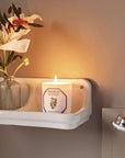 Carriere Freres Orange Blossom Candle showing lit candle in bathroom setting beside a floral arrangement
