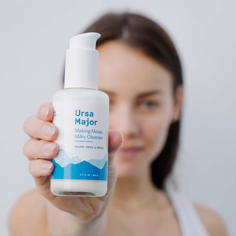 Ursa Major Making Moves Milky Cleanser with blurred model holding product