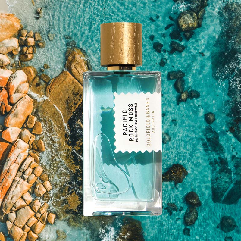Mood shot of Goldfield &amp; Banks Pacific Rock Moss Perfume 100 ml with aerial view of tropical ocean and rocks in the background
