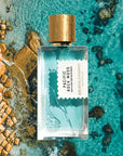 Mood shot of Goldfield & Banks Pacific Rock Moss Perfume 100 ml with aerial view of tropical ocean and rocks in the background