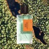 Mood shot of Goldfield & Banks Blue Cypress Perfume 100 ml with aerial view of water and green trees in the background