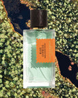Mood shot of Goldfield & Banks Blue Cypress Perfume 100 ml with aerial view of water and green trees in the background