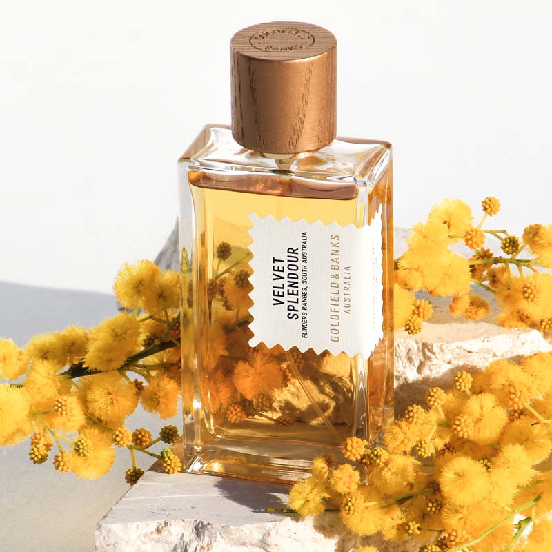 Lifestyle shot of Goldfield &amp; Banks Velvet Splendour Perfume 100 ml on stone slab with yellow flowers in the background and foreground